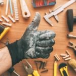 Gloved hand giving a thumbs-up among tools on a workbench, representing DIY home improvement for A-Plus Air Conditioning.
