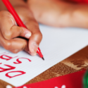 Close-up of a hand writing "DESIRE" on paper with a red pen on a wooden table, related to home services by A-Plus.
