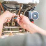 Technician hands performing HVAC equipment maintenance with tools and wiring connections for A-Plus Air Conditioning.