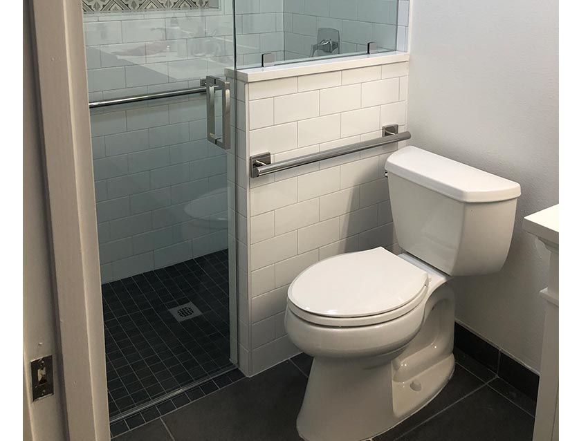 ADA-compliant bathroom featuring a toilet and grab bars for accessibility, designed for aging-in-place renovations by A-Plus Air Conditioning & Home Solutions.