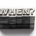 Metal letterpress type reading "WHEN?" showcasing urgency, associated with A-Plus Air Conditioning & Home Solutions services.