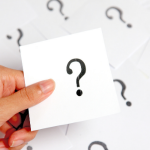 Hand holding a white card with a large question mark, surrounded by scattered cards, linked to home service inquiries.