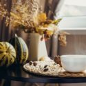 Cozy autumn scene with a white bowl, coffee beans, dried flowers, and gourds near HVAC service materials.