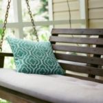 Swinging bench with teal cushion in a home setting, showcasing HVAC-related comfort and natural light.