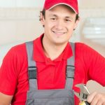 Male HVAC technician in a red cap and shirt holding an adjustable wrench, ready for home maintenance services.