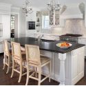 Modern kitchen island with seating, white cabinetry, and granite countertop for energy-efficient home solutions.