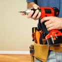 Person holding a bright red power drill, ready for home improvement projects in an indoor setting; A-Plus HVAC services.