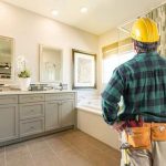 Construction worker evaluating a modern bathroom with vanity and sinks for A-Plus Air Conditioning & Home Solutions.