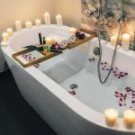 Freestanding bathtub with candles and bath tray, representing air conditioning maintenance for home improvement projects.