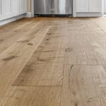 Wooden floor in a clean kitchen with white cabinetry and stainless steel appliances, ideal for home improvement projects.